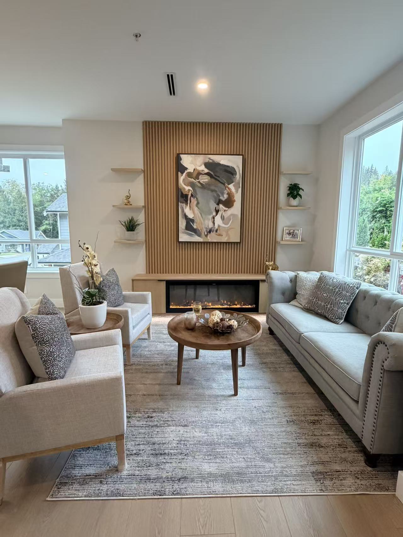 Finished living room with custom fluted wood fireplace wall, floating shelves and low cabinetry