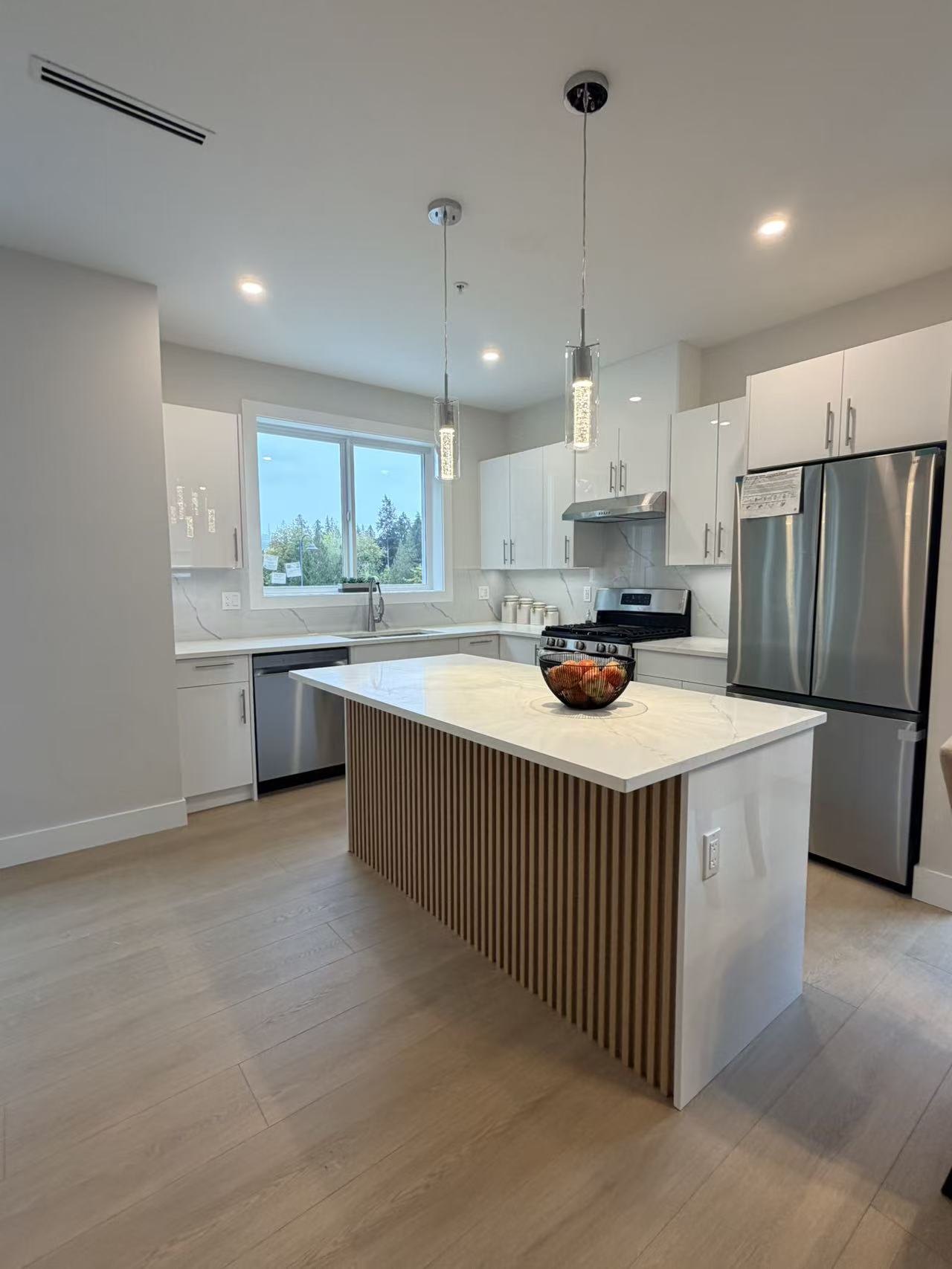 Modern white kitchen cabinetry with a custom fluted wood island and stone countertop
